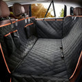 Black quilted dog seat cover with orange piping fitted across a car back seat, hanging from the headrests