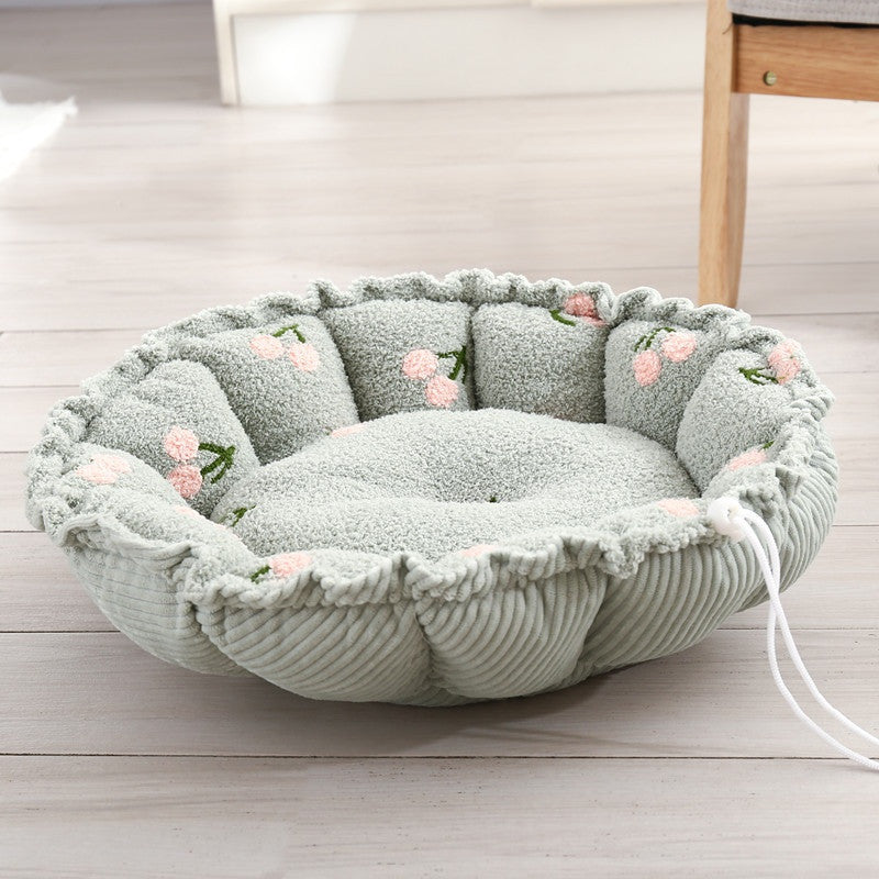 Round petal-shaped plush cat nest, mint green with pink fruit motifs, with a white drawstring
