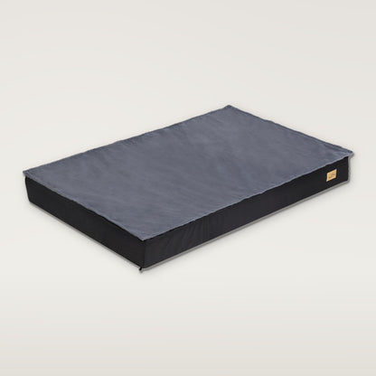 Flat dog mattress bed with a grey plush top on a black base