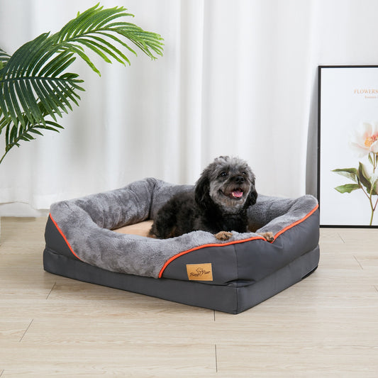 Dark grey rectangular bolster dog bed with orange piping and a beige plush centre, a small black dog lying in it