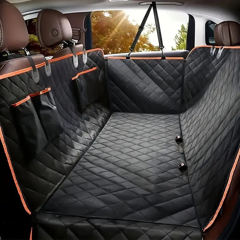 Black quilted dog seat cover with orange piping fitted across a car back seat, hanging from the headrests
