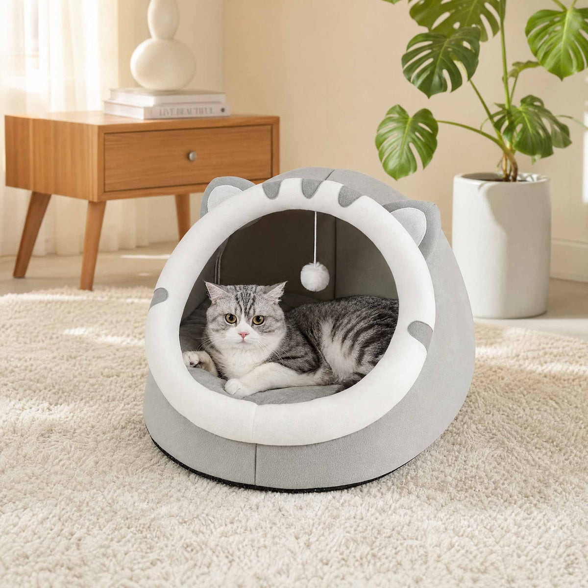 The grey cat-ear cave on a rug in a living room with a cat inside