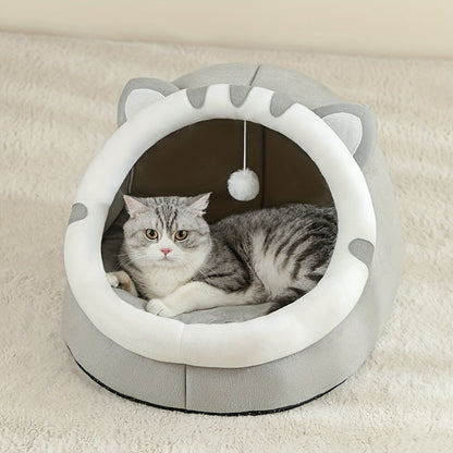 Grey and white cat-ear cave with a round opening and a hanging pom toy, a tabby cat lying inside