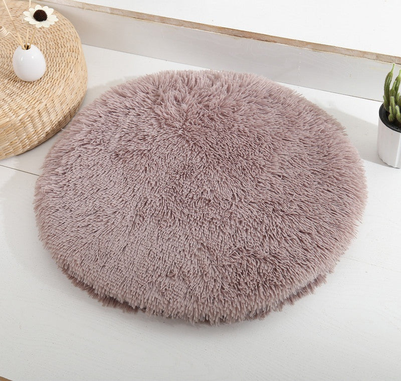 Round long-pile plush cat cushion in taupe brown on a white table