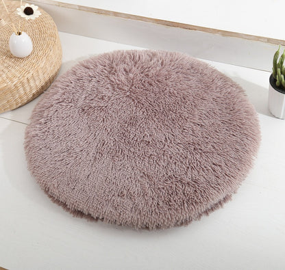 Round long-pile plush cat cushion in taupe brown on a white table