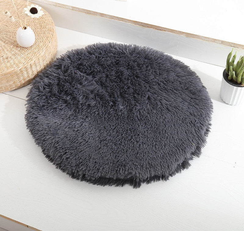 Round long-pile plush cat cushion in charcoal grey on a white table