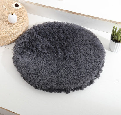 Round long-pile plush cat cushion in charcoal grey on a white table