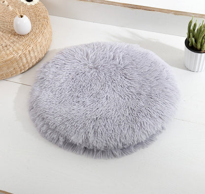 Round long-pile plush cat cushion in light grey on a white table