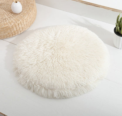 Round long-pile plush cat cushion in white on a white table