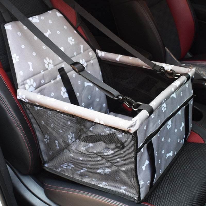 Grey car booster box with white paw and bone prints and a mesh front, hung on a car seat