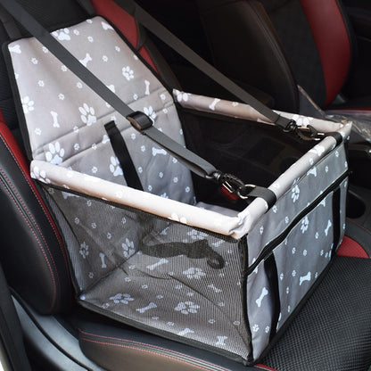 Grey car booster box with white paw and bone prints and a mesh front, hung on a car seat