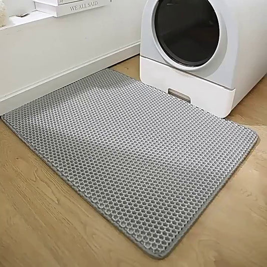 Grey honeycomb EVA litter mat on a wood floor in front of a white litter box