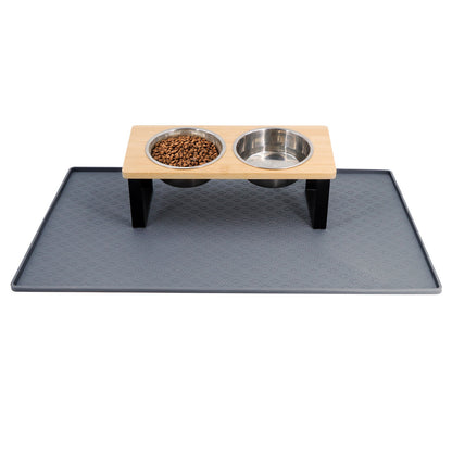 Raised bamboo feeding stand with two stainless bowls standing on a grey silicone mat