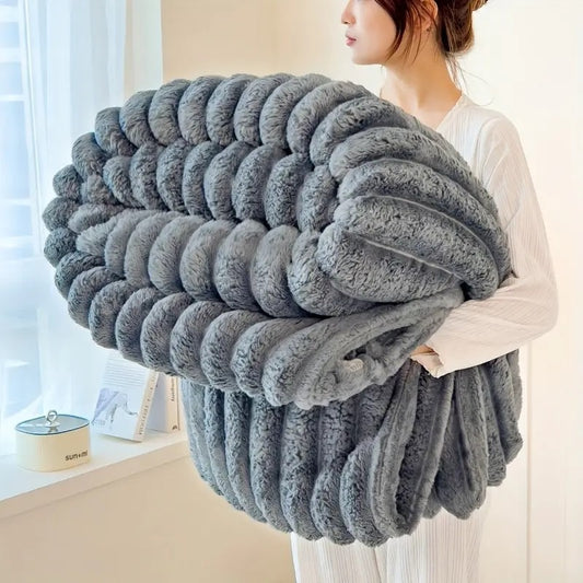 Person in a white long-sleeved top holding a folded grey ribbed plush throw blanket