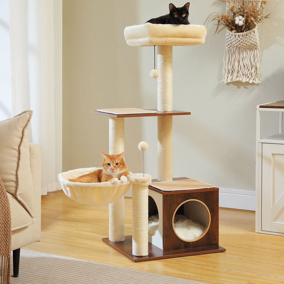 Brown and cream wood cat tower in a living room with a black cat on the top perch and a ginger cat in the basket