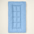 Light-blue quilted rectangular pet mat seen from above on a warm off-white backdrop