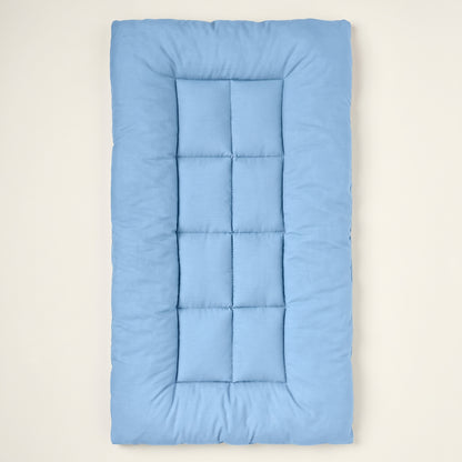 Light-blue quilted rectangular pet mat seen from above on a warm off-white backdrop