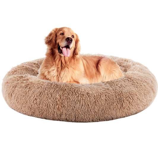 A golden retriever lies in a light brown long-pile faux-fur donut bed on a white background