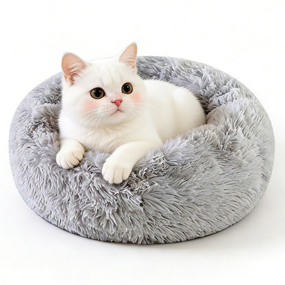 A white cat lies in a grey long-pile donut bed on a white background