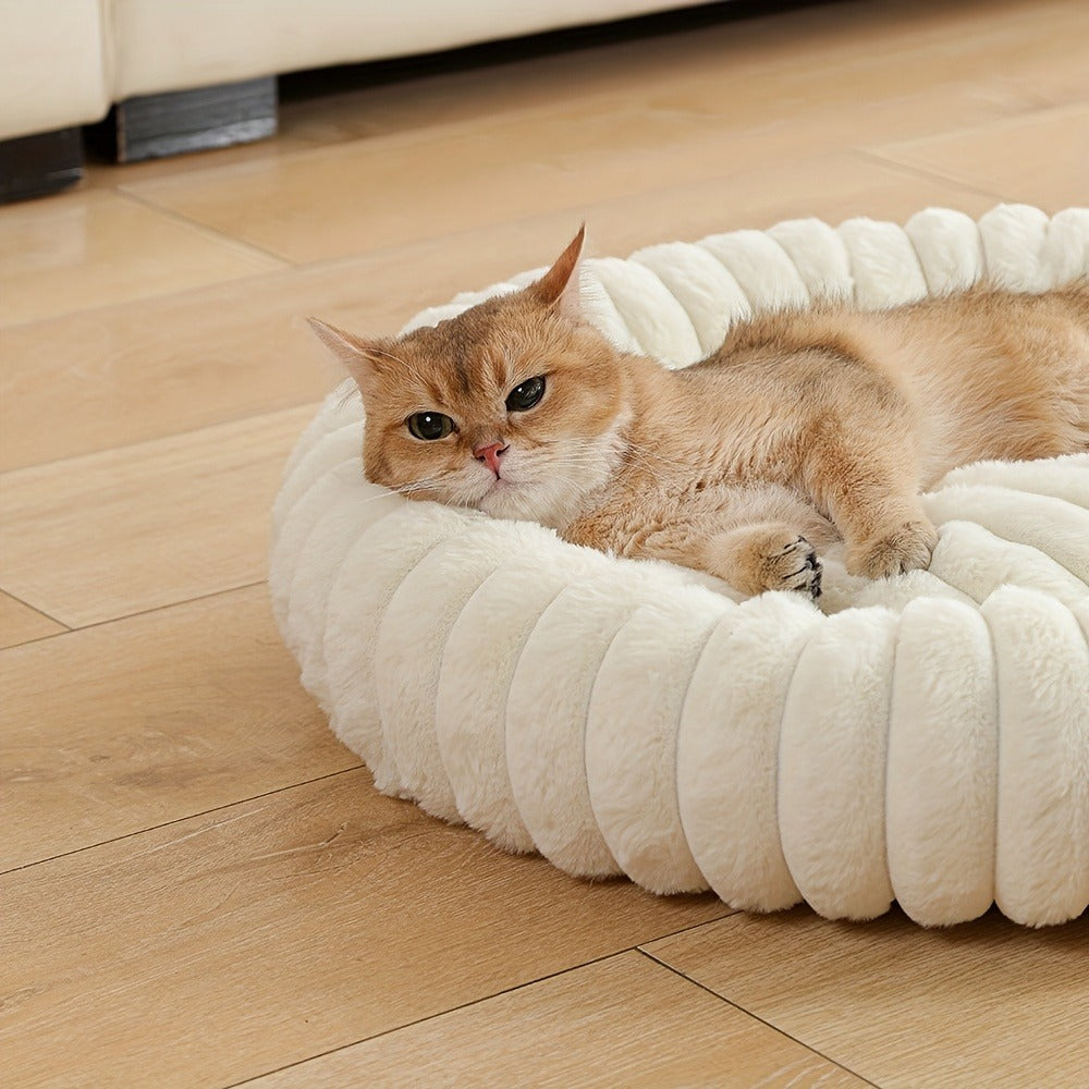 Close-up of a ginger cat resting its head on the cream tube rim of the bed
