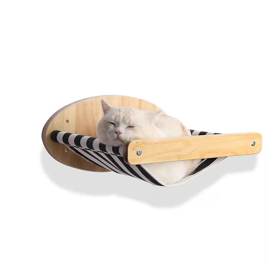 Wall-mounted cat hammock with a black and white striped canvas sling, oval wooden wall plate and front wooden bar, a white cat asleep in it